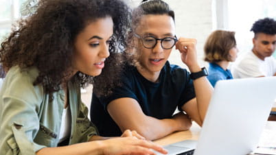 two persons in front of a laptop two persons in front of a laptop